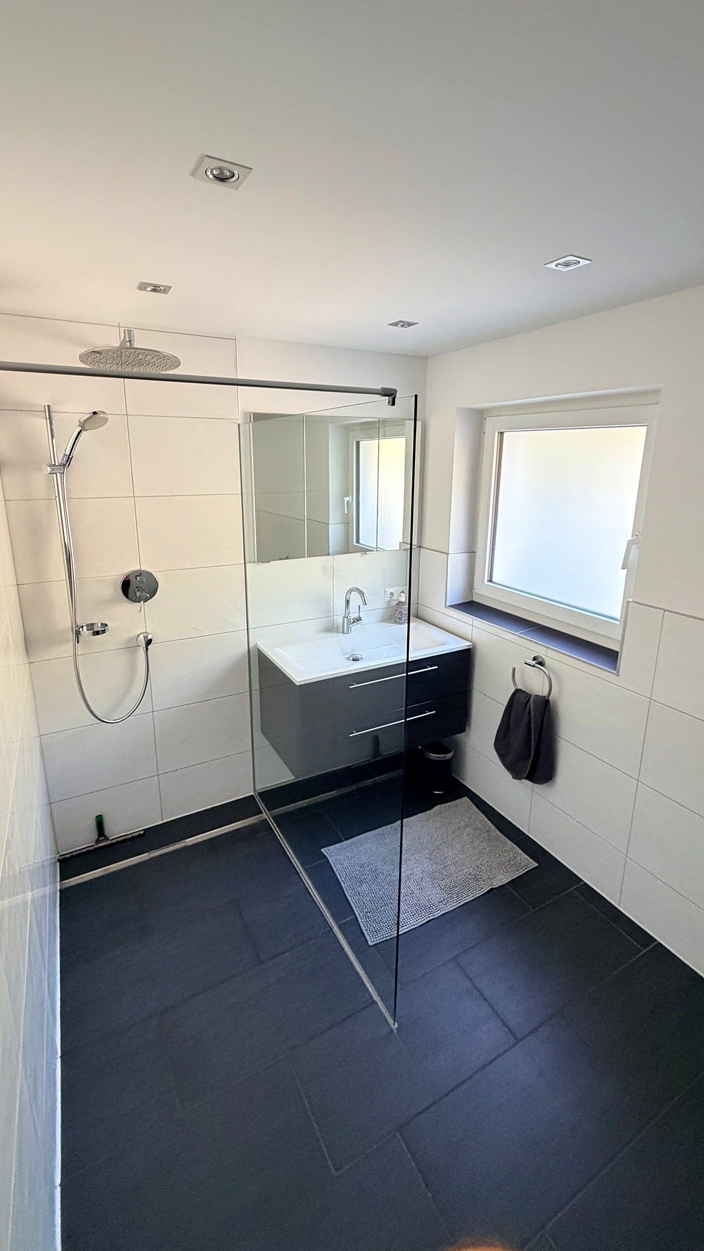 Badezimmer mit bodengleicher Glasdusche, Regendusche und Waschtisch