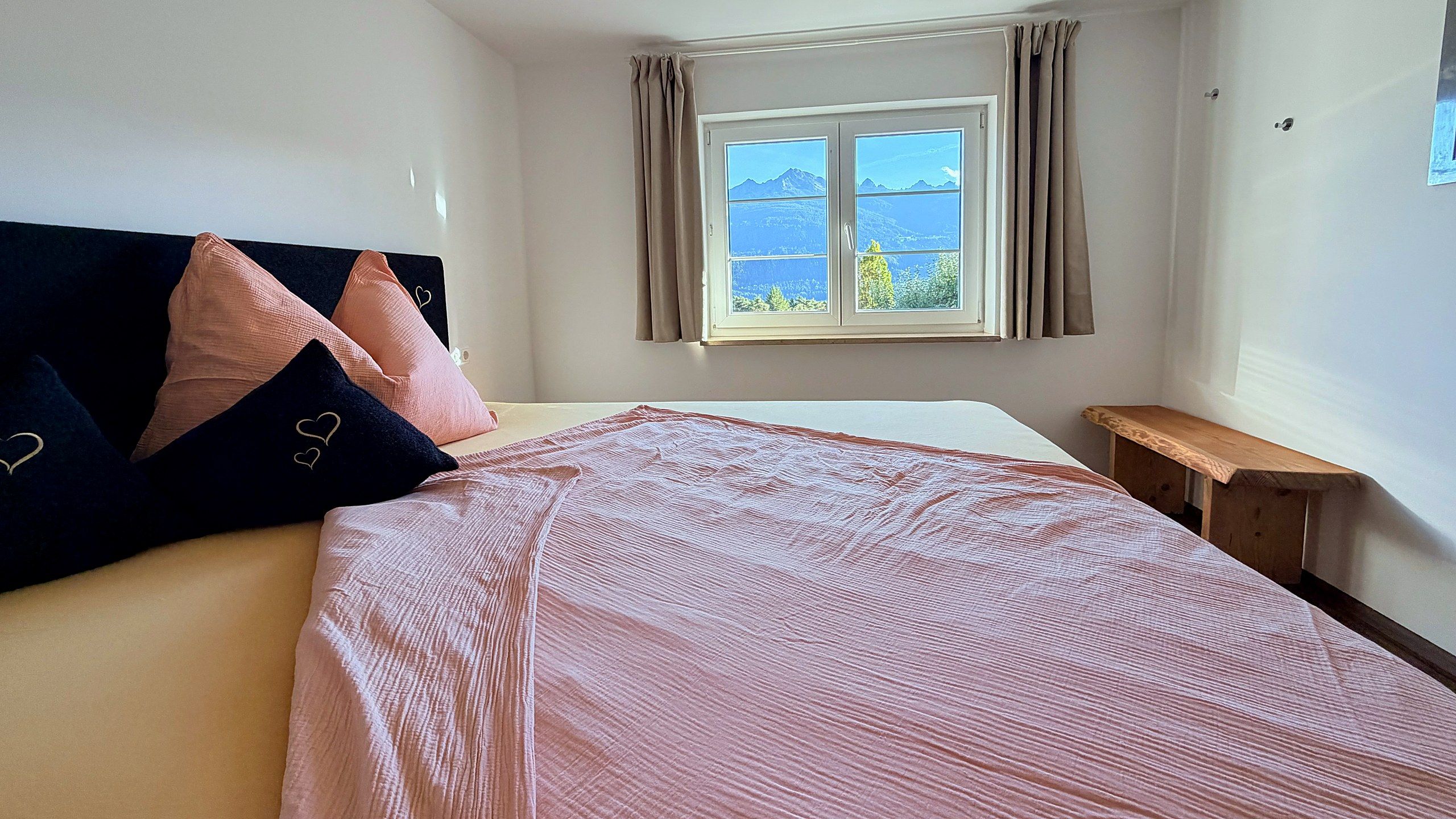 Doppelbett mit Blick durchs Fenster auf die Berge