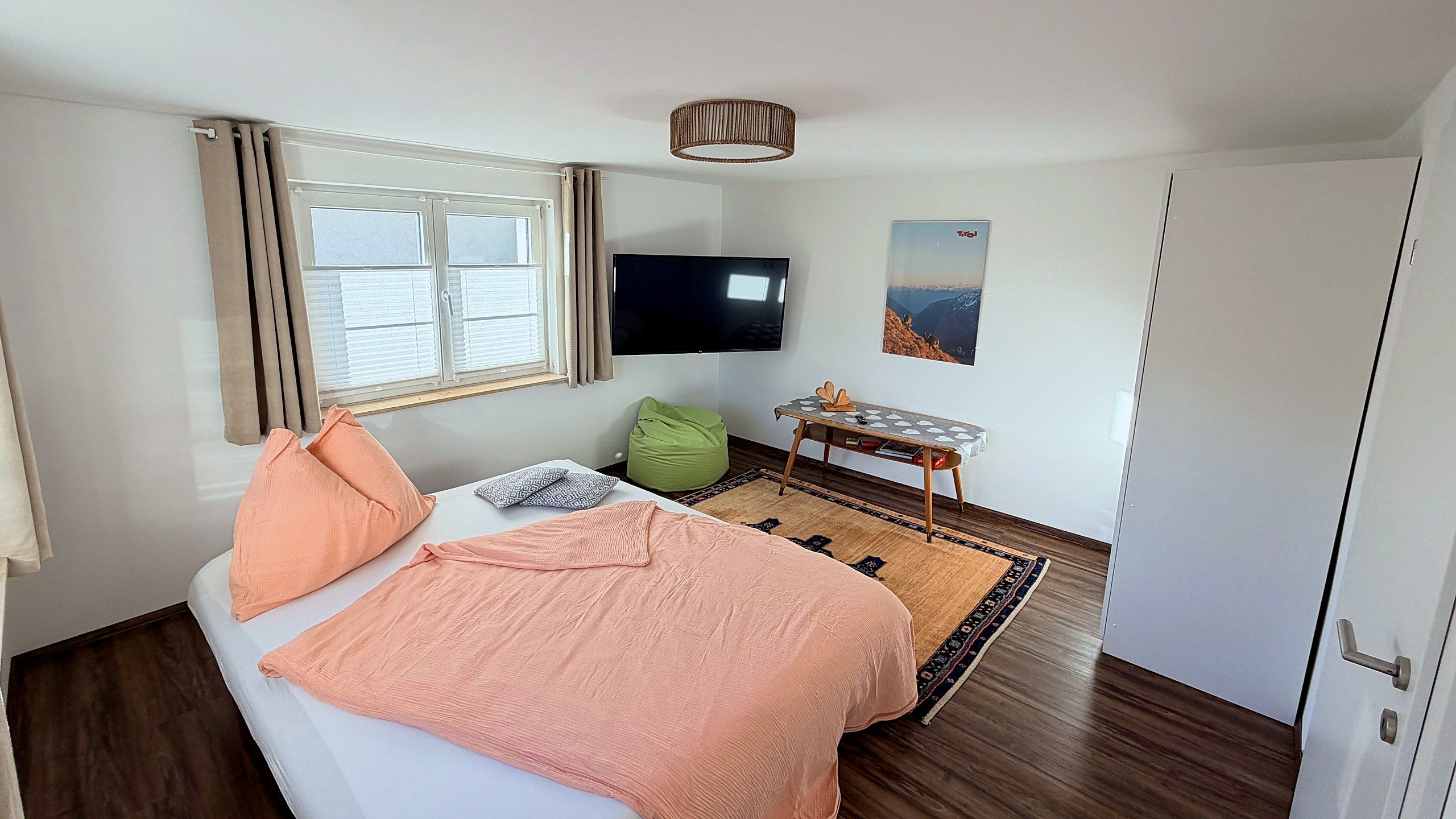 Wohnzimmer mit ausgezogenem Schlafsofa, Fernseher und Teppich